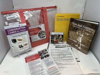 ""Early Stages: Nostalgia Pack red lined clear bag sitting behind books, cards, and CDs on white background""