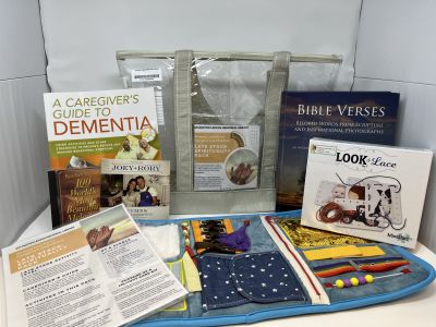 "Late Stage: Spirituality Pack tan lined clear bag sitting behind books, cards, and CDs on white background"